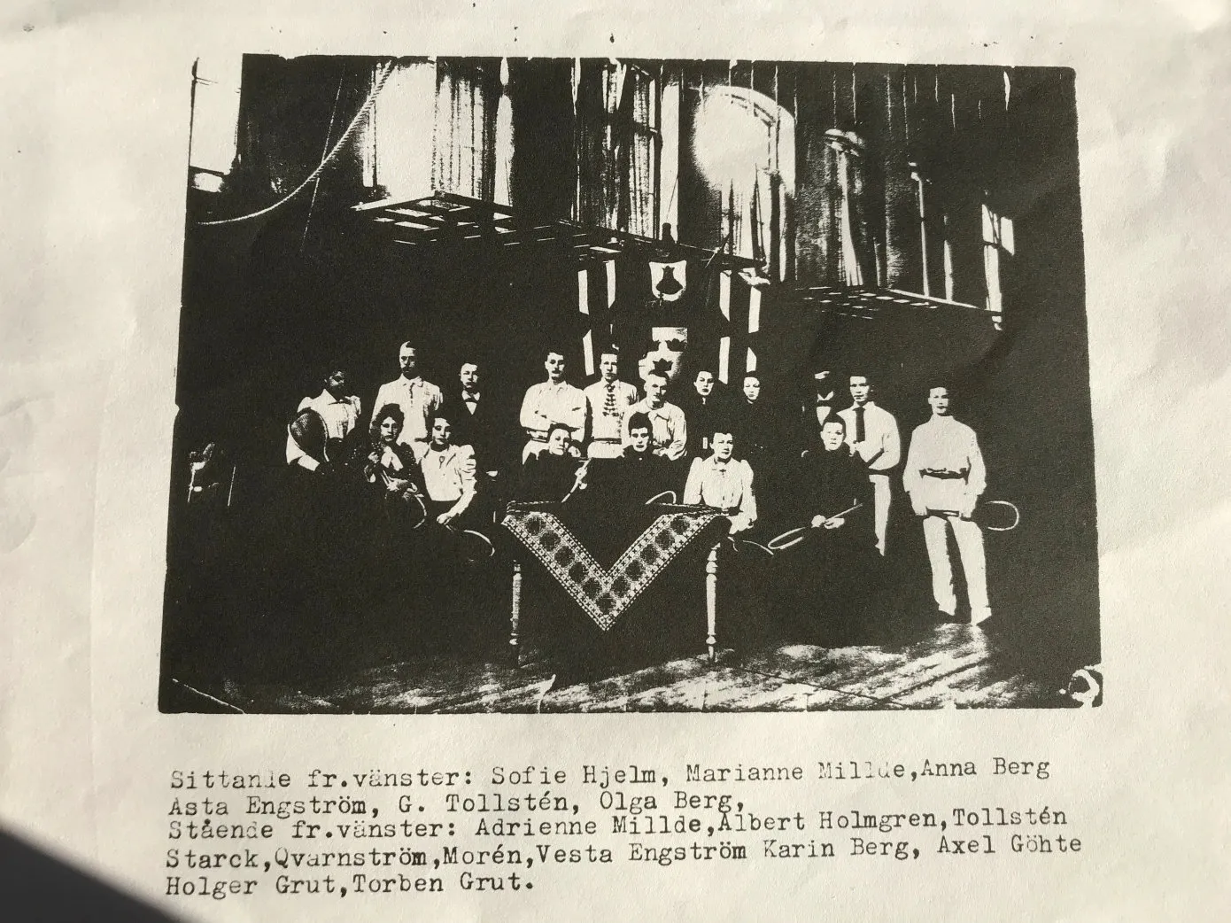 Gruppfoto från klubbens första år: damer och herrar, flera med racketar, framför en dekorerad vägg.