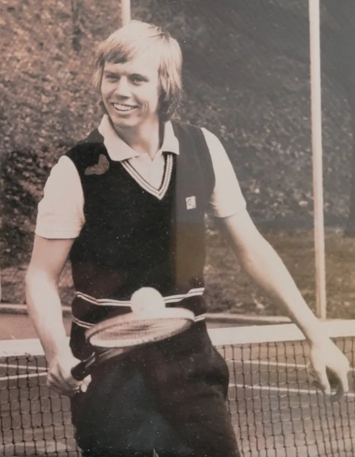 A young player in a sweater vest at the net.